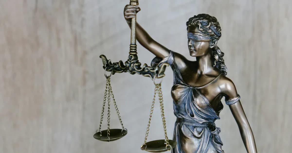 Estatua de la Justicia con los ojos vendados y balanza sobre fondo claro